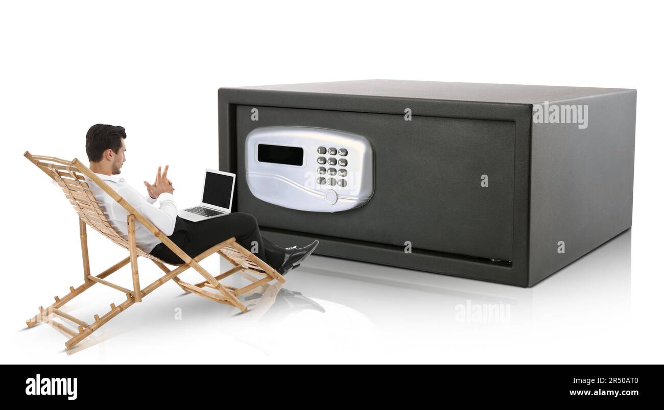 Finanzielle Sicherheit, Geld behalten. Aufmerksamer Geschäftsmann mit Laptop vor einem großen Stahlsafe, weißer Hintergrund Stockfoto