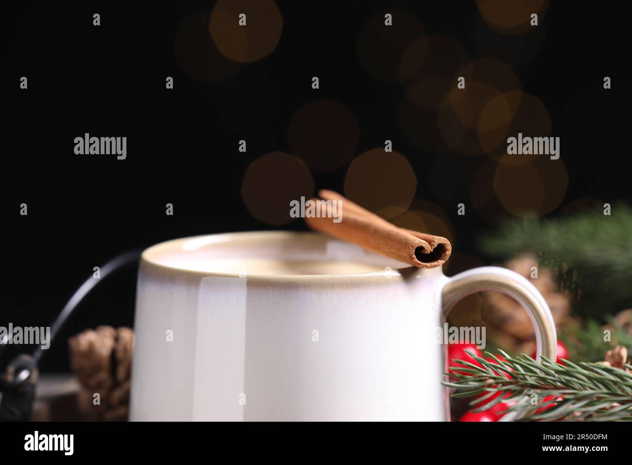 Leckerer Eierpunsch mit Zimtstäbchen gegen verschwommenes Licht, Nahaufnahme Stockfoto