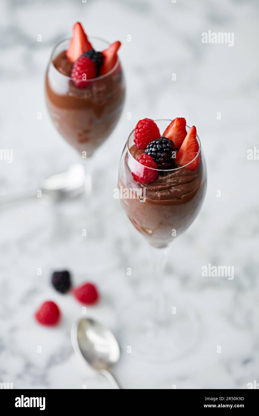 Schokoladenmousse garniert mit Erdbeeren und Himbeeren, serviert in einem Champagnerglas Stockfoto