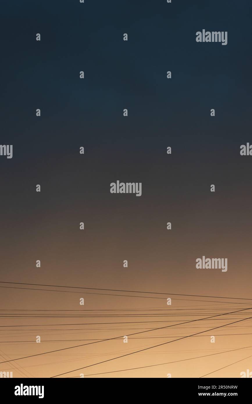 Urbaner Himmel mit Drähten an einem regnerischen Abend, abstrakter vertikaler Fotohintergrund Stockfoto