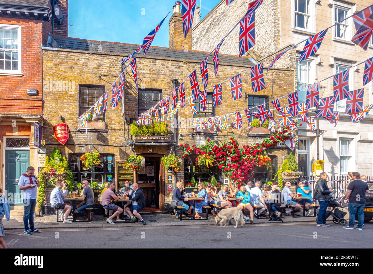 Vor dem Pub Two Brewers in Windsor, Berkshire, Großbritannien, herrscht eine lebhafte Atmosphäre, in der die Menschen im Biergarten trinken und die Straße mit Union Jack Wings verzieren. Stockfoto