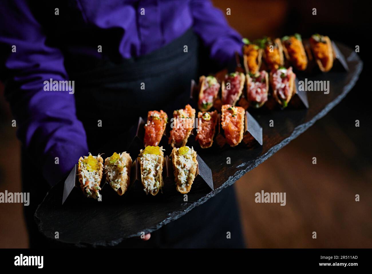 Verschiedene Tacos mit Meeresfrüchten werden als Vorspeisen auf einer Schieferplatte serviert Stockfoto