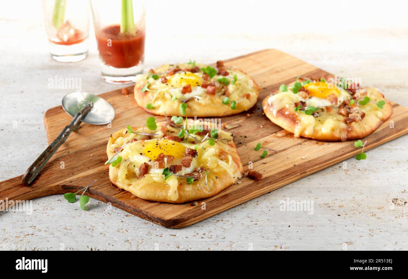 Mini-Pizza mit Spiegeleiern und gewürfeltem Speck Stockfoto