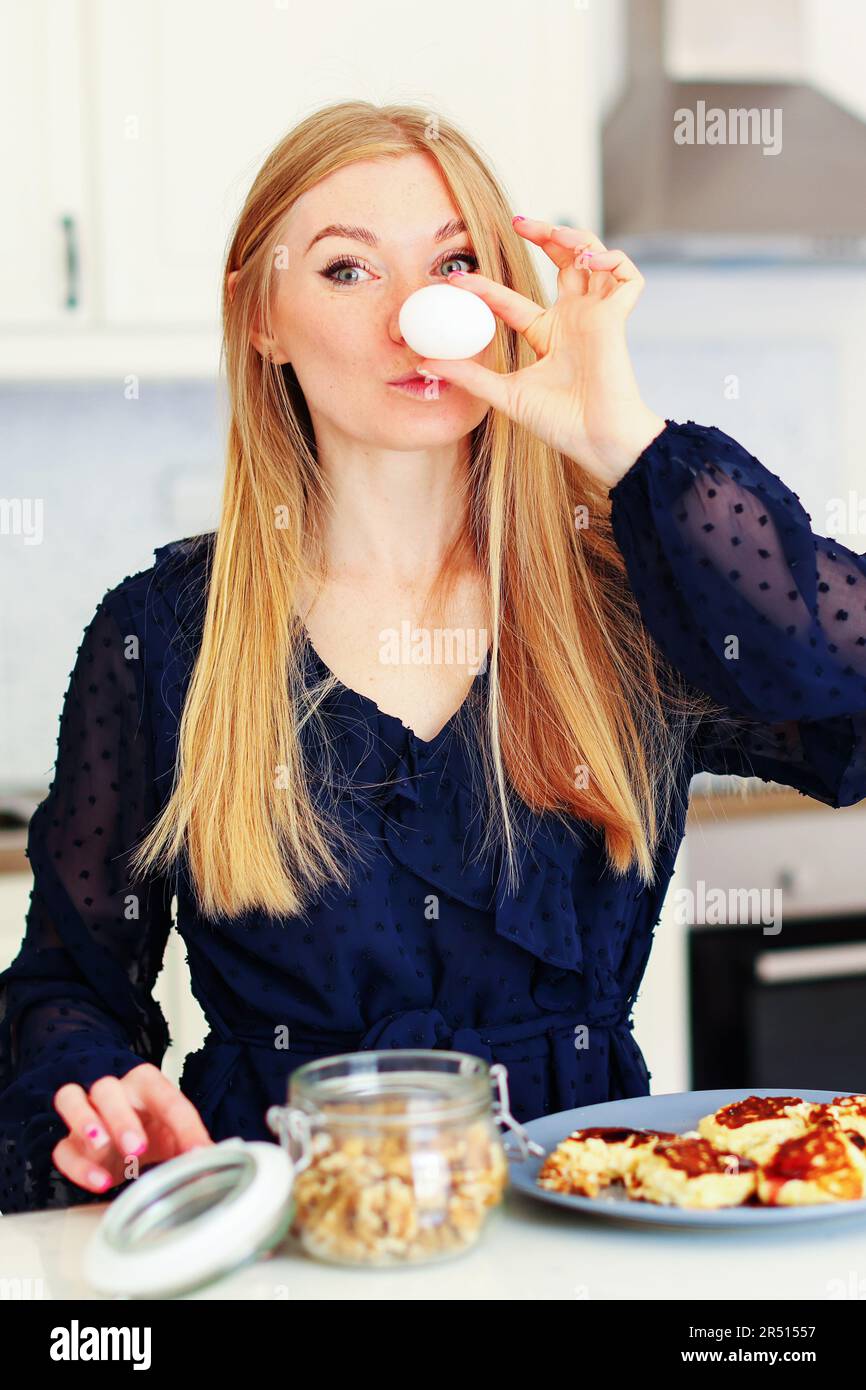 Eine glückliche junge Frau hält das Ei und macht sich keine Mühe, das Frühstück zuzubereiten Stockfoto