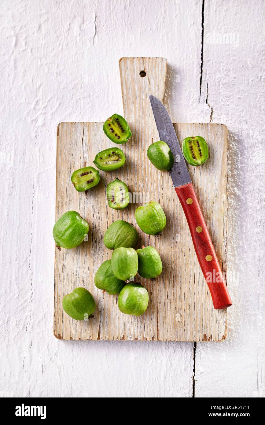 Kiwibeeren, teilweise halbiert, auf Holzbrett Stockfoto