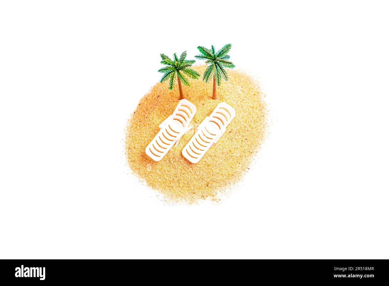 Draufsicht eines Miniaturspielzeugs mit Sonnenliegen und Palmenfiguren auf einem kleinen Sandhaufen, isoliert auf weißem Hintergrund. Kreatives Tro Stockfoto