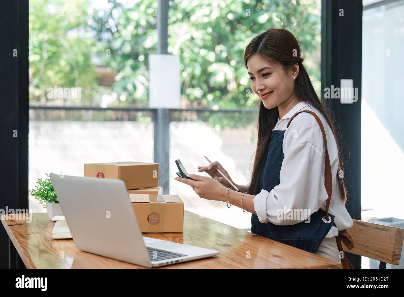 Startup-Unternehmen erfolgreicher Inhaber eines kleinen Unternehmens die junge asiatische Frau sitzt mit Laptop, Taschenrechner und Karton zu Hause und bereitet den Versand an den Kunden, das Verkäufergeschäft vor Stockfoto