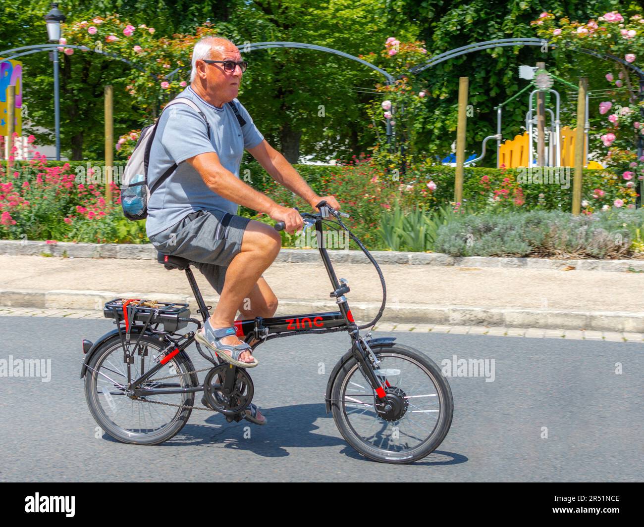 Mann auf dem „Zinc“-E-Bike, der durch die Stadt fährt - La Roche Posay, Vienne (86), Frankreich. Stockfoto