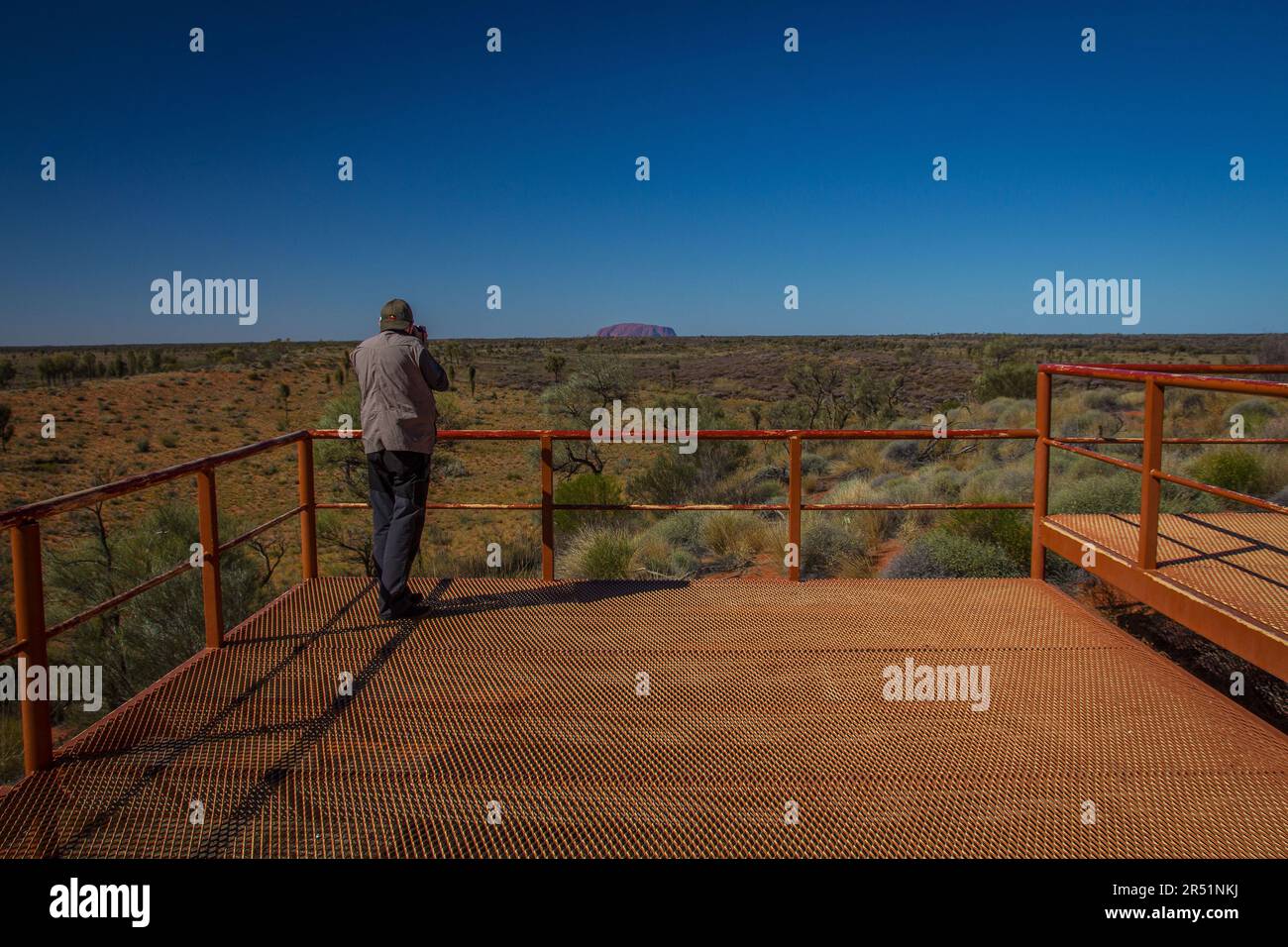 Ein Mann beobachtet Uluru aus der Ferne, Australien Stockfoto