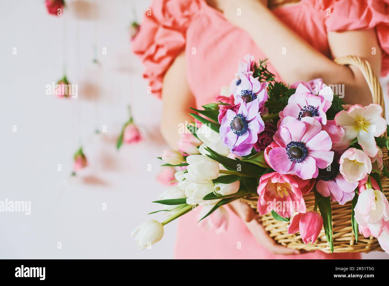 Eine Frau mit einem Korb mit vielen bunten Blumen im Frühlingshintergrund Stockfoto