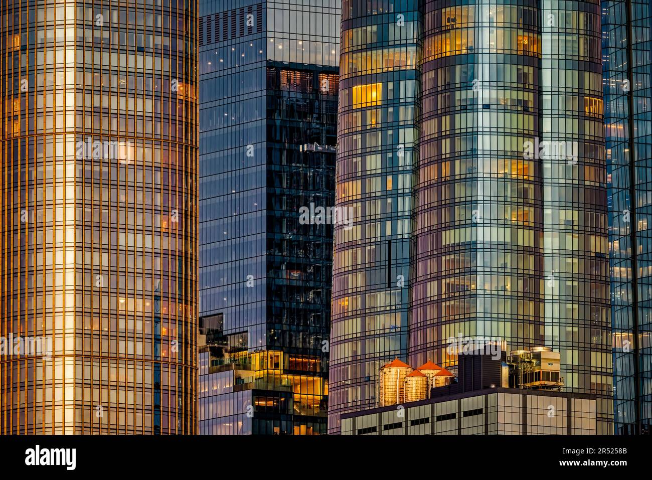 NYC Modern Architecture - die Farben der untergehenden Sonne und des Himmels spiegeln sich in den Glasscheiben wider, aus denen die meisten Wolkenkratzer in Hudson Yards bestehen. Stockfoto