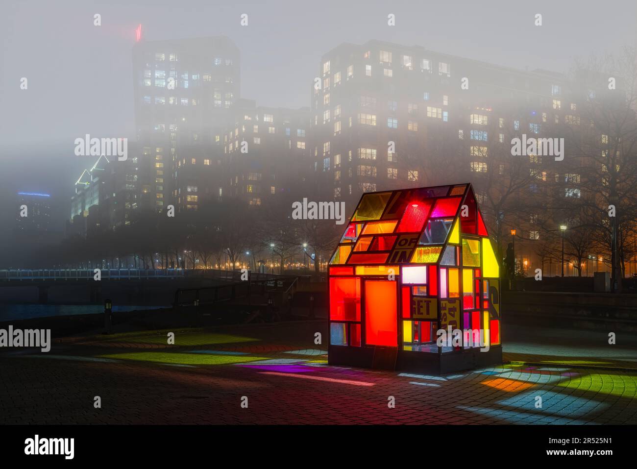 Farbenfrohes Glashaus - die beleuchtete Skulptur des Taxicab-Glashauses aus dem Jahr Hi5 von Tom Fruin. Der starke Nebel am Hudson River bedeckt die Skyline von Hoboken und Stockfoto