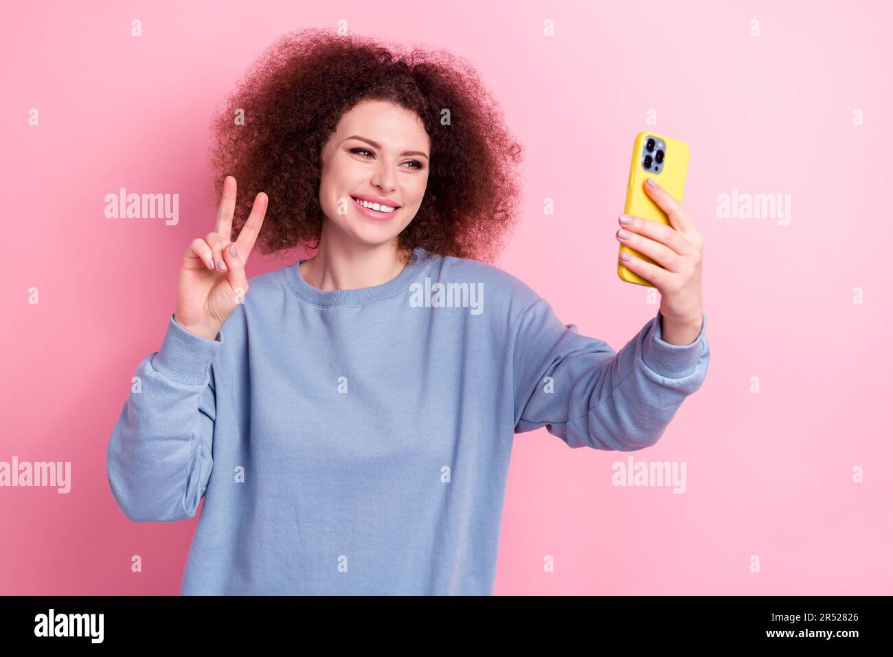 Foto eines jungen Mädchens, brünett, mit V-Zeichen-Symbol, das Live-Stream-Telefon-Anhänger mit Grüßen auf pinkfarbenem Hintergrund ausstrahlt Stockfoto