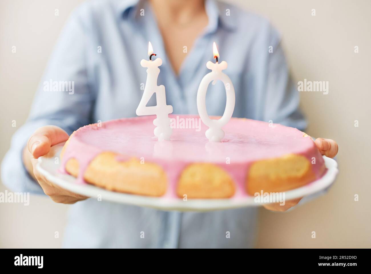 Glückliche 40-jährige Frau, die Kuchen mit Kerzen hält Stockfoto