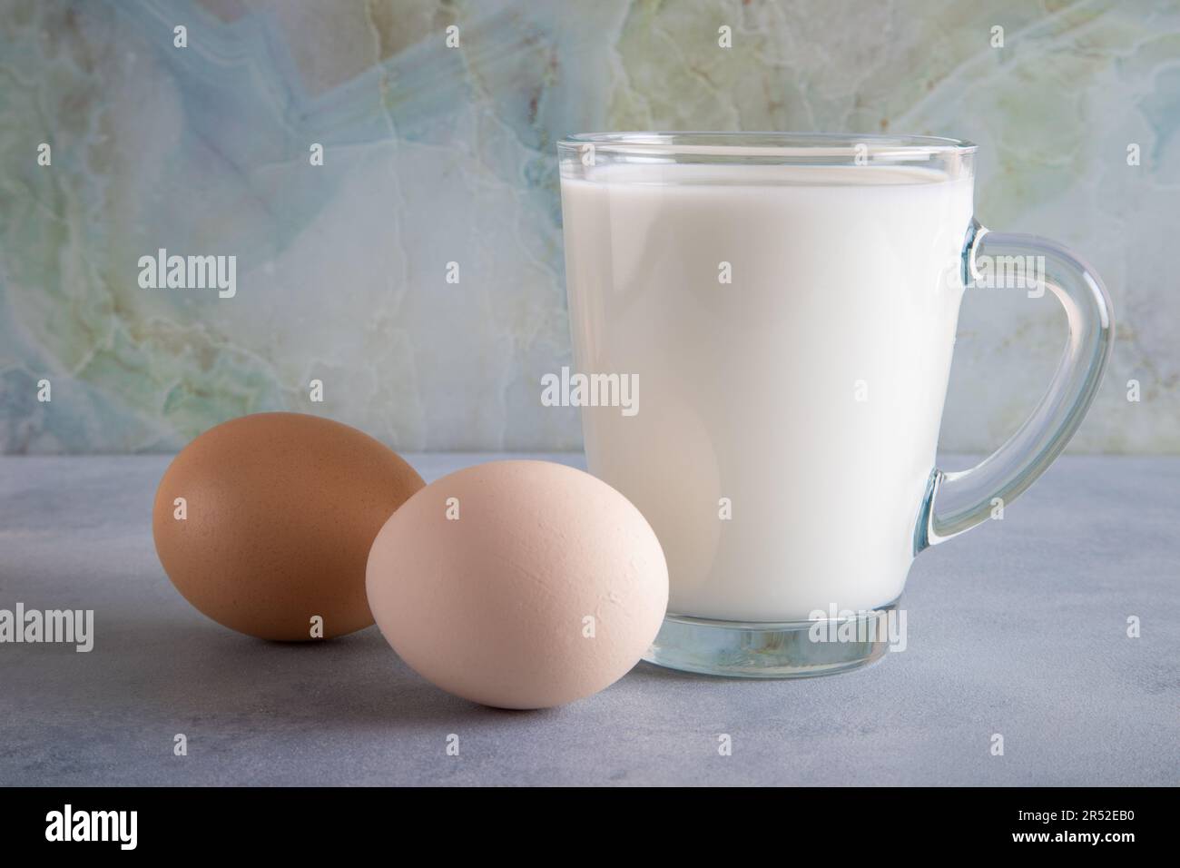 Ein Glas Milch und zwei Eier auf dem blauen Tisch Stockfoto