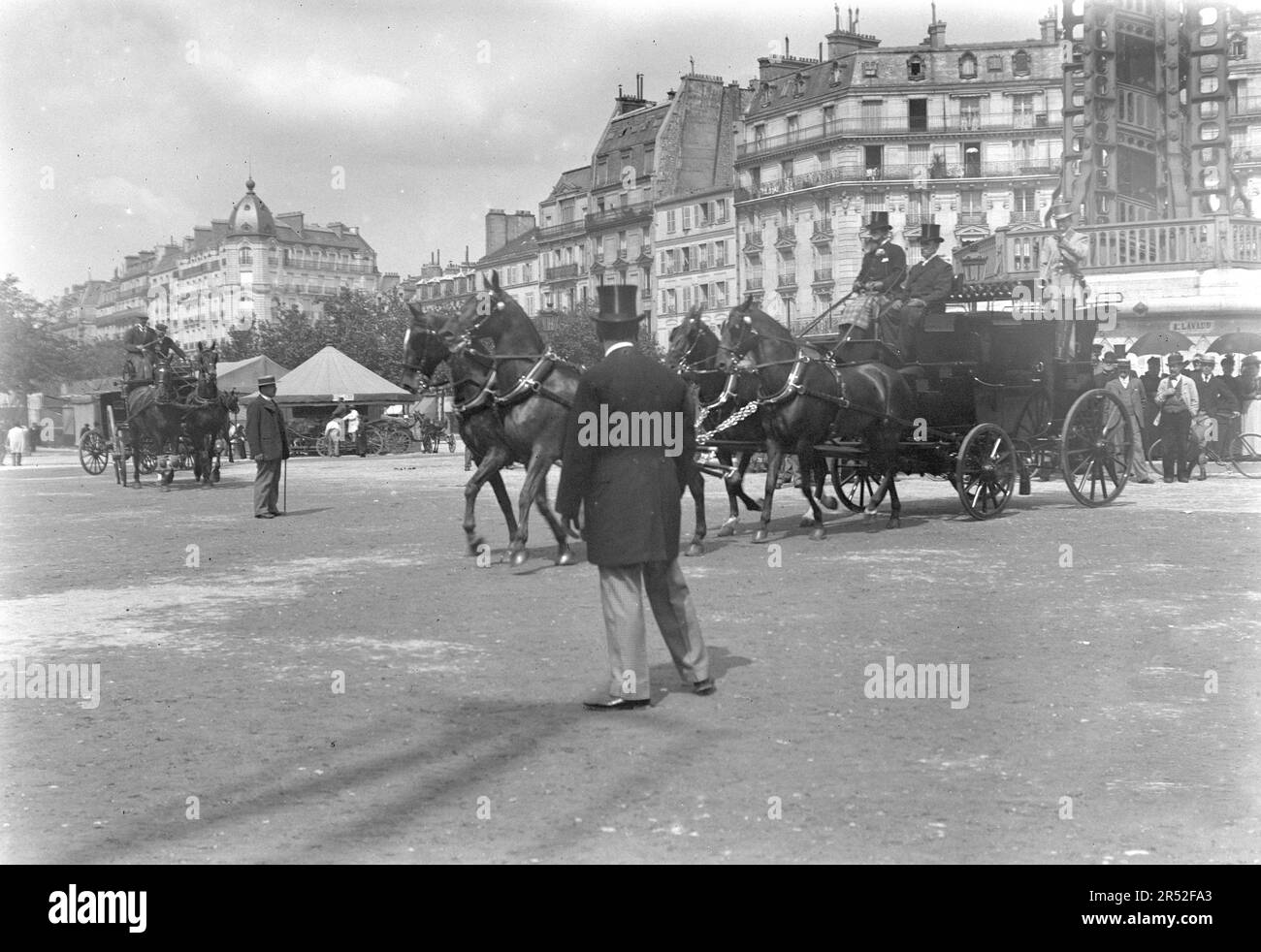 Ein Mann mit einem Hut und einem Anzug, der in Paris reinspaziert. Neben den Kutschen und Hausmannsgebäuden. Anfang des 20. Jahrhunderts. Altes Foto. Stockfoto