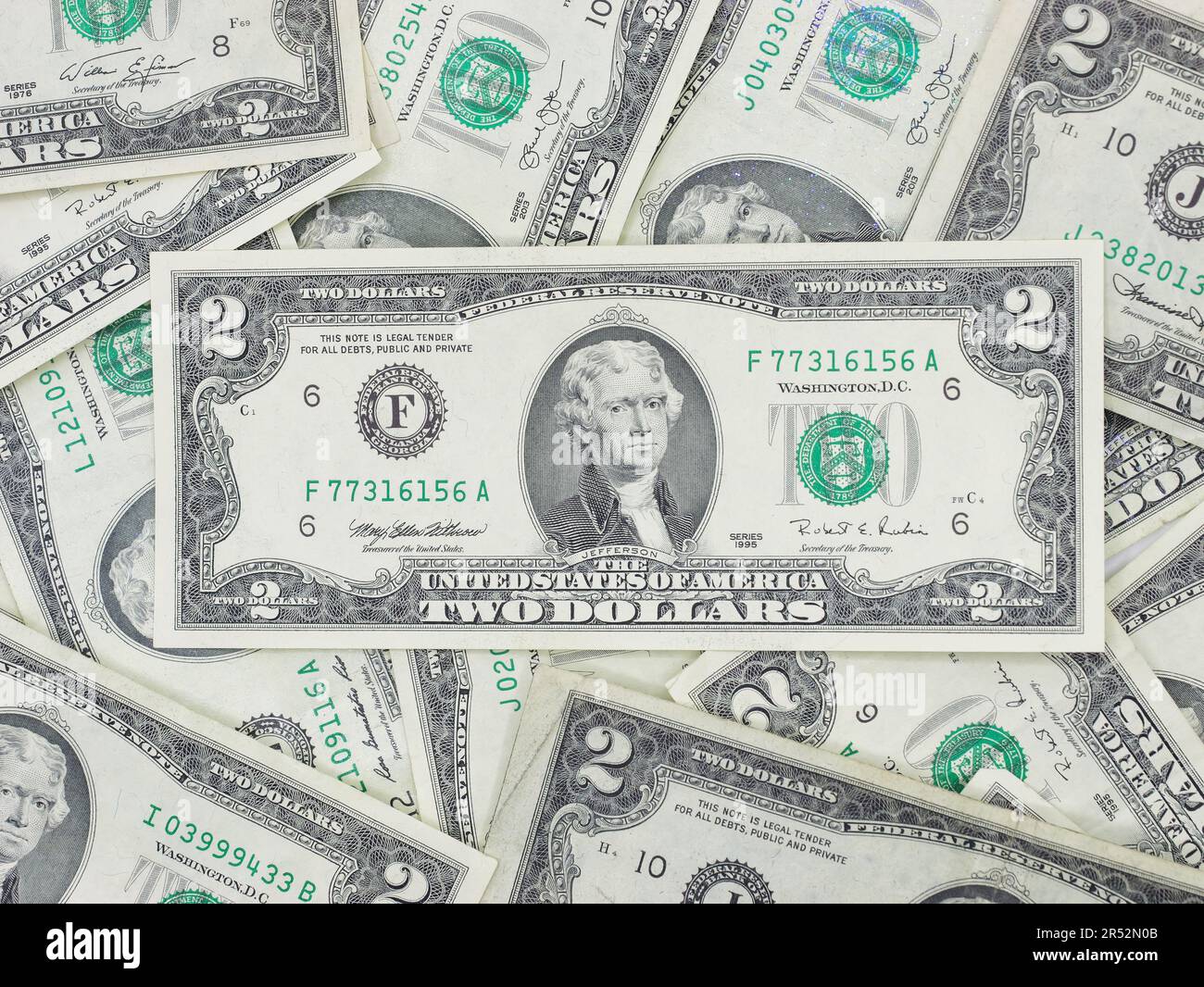 Zahlreiche zwei-Dollar-Scheine, die flach auf einem Tisch liegen – ungerade, einzigartige US-Währung Stockfoto