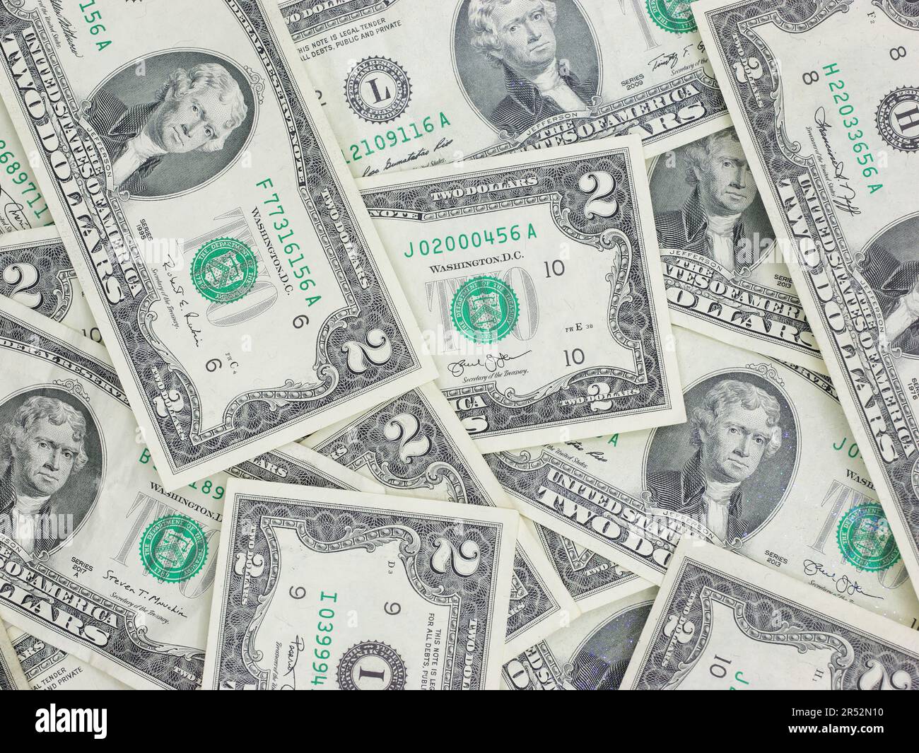 Zahlreiche zwei-Dollar-Scheine, die flach auf einem Tisch liegen – ungerade, einzigartige US-Währung Stockfoto