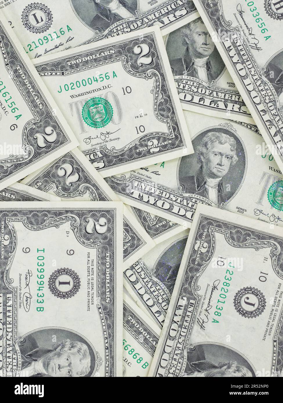 Zahlreiche zwei-Dollar-Scheine, die flach auf einem Tisch liegen – ungerade, einzigartige US-Währung Stockfoto