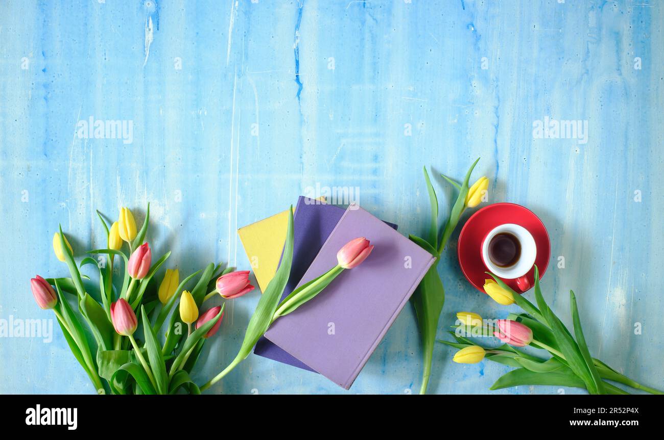 Wunderschöne Frühlingsblumen, eine Reihe bunter Tulpenblumen mit Büchern und einer Tasse Kaffee auf blauem Hintergrund, Konzept, flach liegend, Negativbereich, kostenlose Kopie Stockfoto