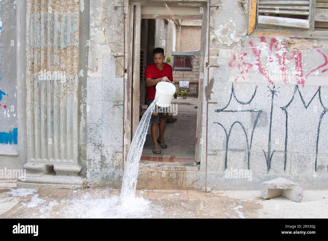 Eine Frau reinigt ihr Haus, indem sie Wasser über den Boden in ihrem Haus in Havanna, Kuba, wirft. Stockfoto