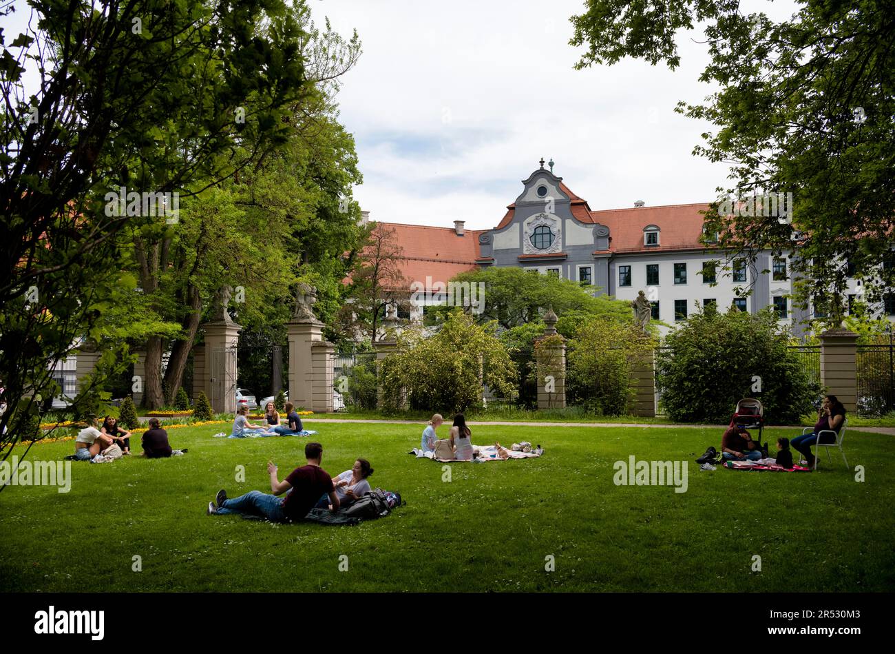 Gäste, die das warme Wetter genießen und sich im Hofgarten, Augsburg, Bayern, entspannen Stockfoto