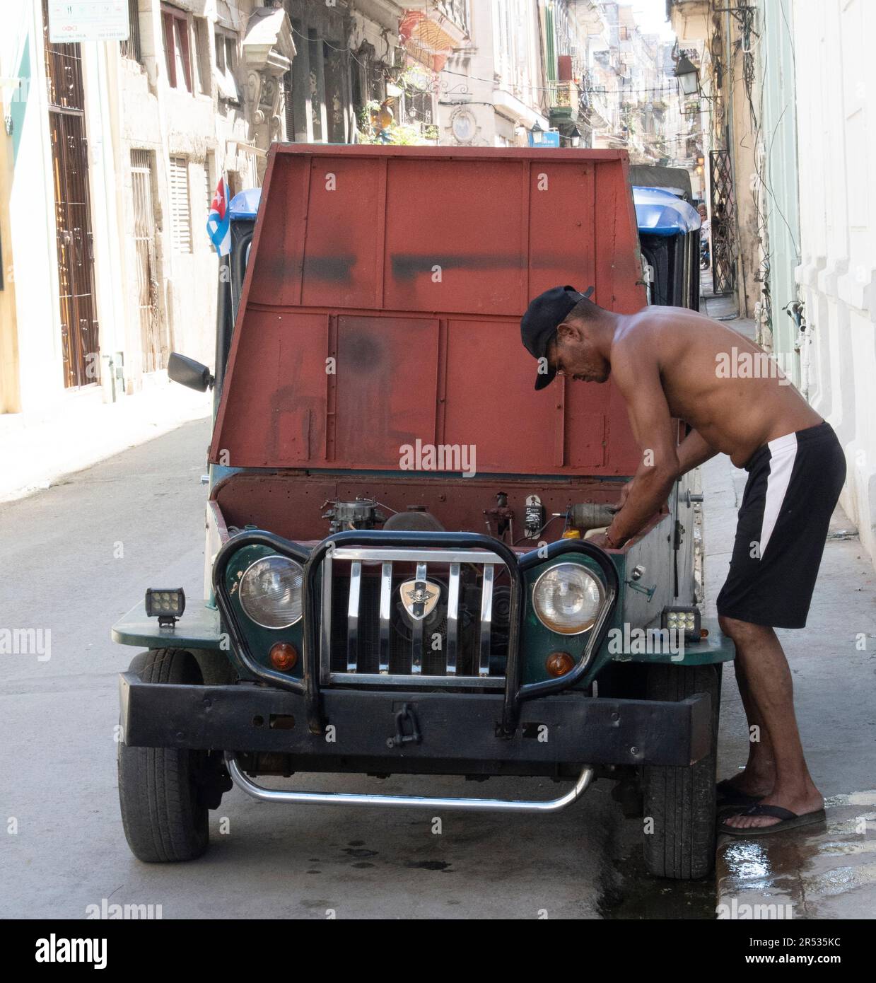 Ein Kubaner, der an seinem alten Auto auf der Straße in Havanna, Kuba, arbeitet. Stockfoto