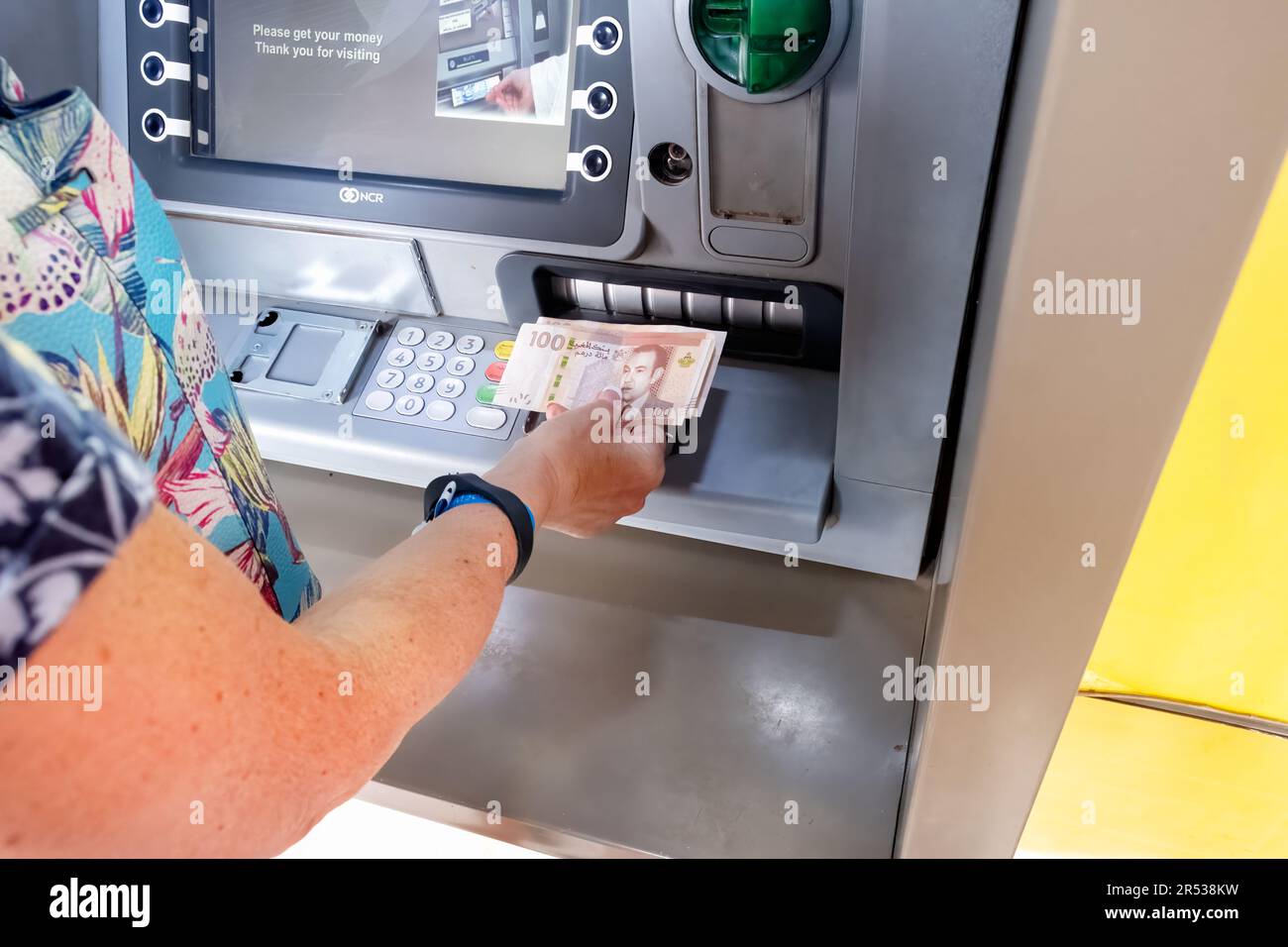 Eine weibliche Touristin, die Bargeld in Dirham-Scheinen von einem Geldautomaten in Marrakesch, Marokko, abhebt. Die Maschinen sind mehrsprachig und weit verbreitet Stockfoto