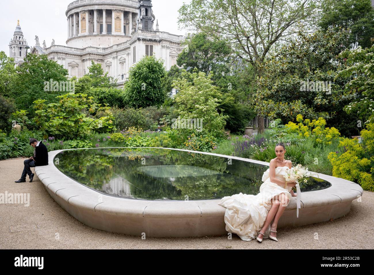 Ein junges weibliches Model gibt sich als Hochzeitsbraut für ein Fotoshooting in der Nähe der Kuppelarchitektur der St Paul's Cathedral in der City of London, dem Finanzviertel der Hauptstadt, am 31. Mai 2023 in London, England aus. Stockfoto