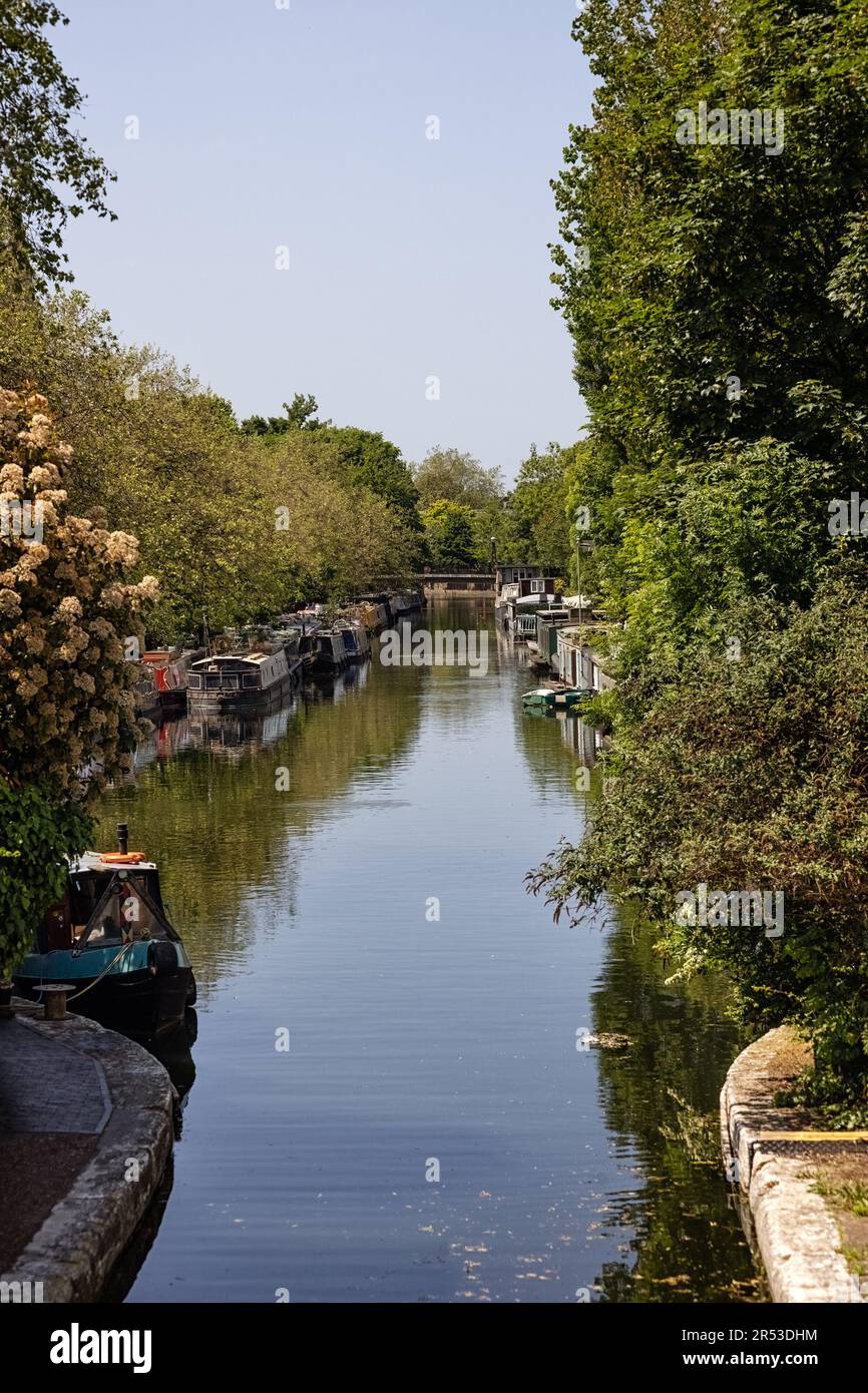 LONDON, Großbritannien - 27. MAI 2023: Blick auf den Grand Union Canal, gesäumt mit festgefahrenen Schmalbooten, wo er in Little Venice in den Regents Canal mündet. Stockfoto