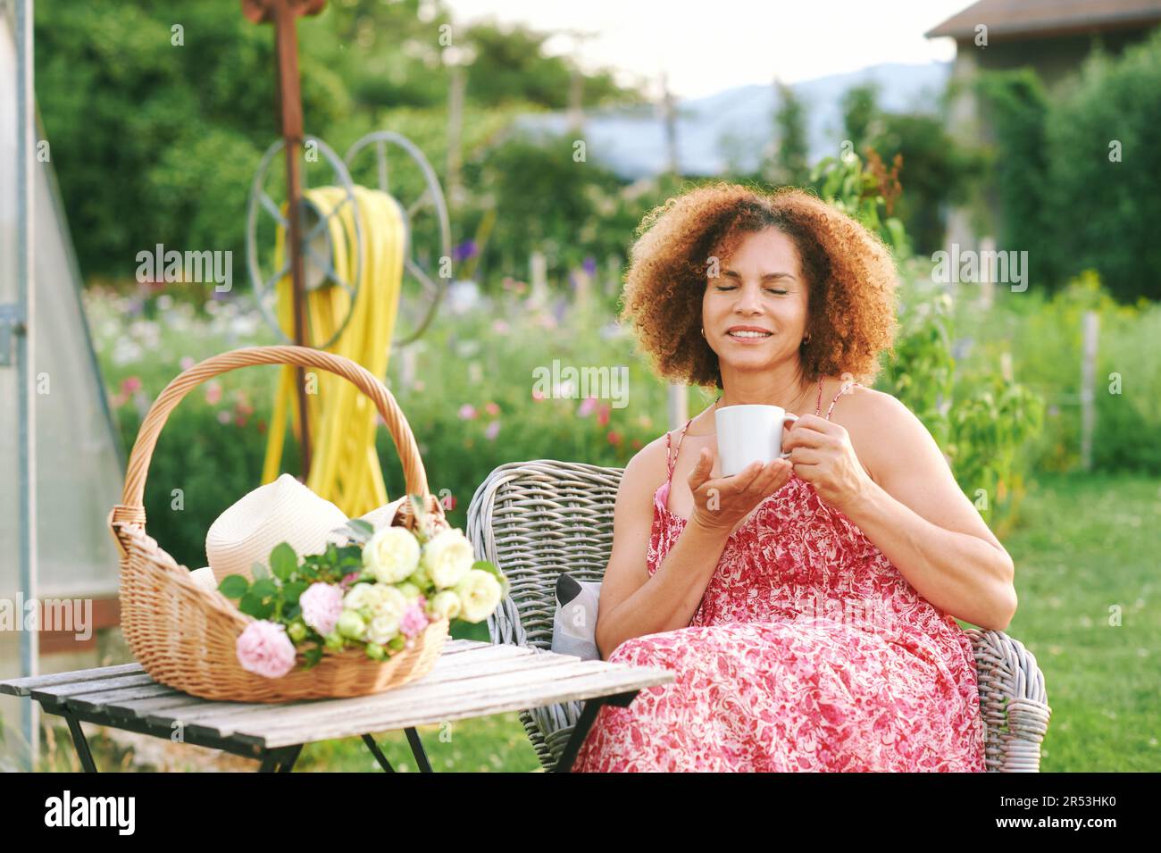 Außenporträt einer schönen, reifen Frau, die im Sommergarten ruht, in ...