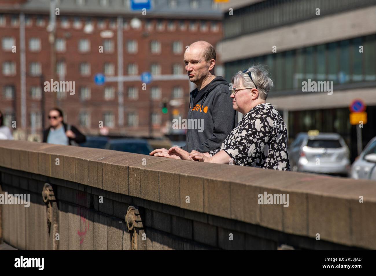Erwachsenenpaar, das Kaisaniemenlahti auf der Pitkäsilta-Brücke im Hakaniemi-Viertel von Helsinki, Finnland, besichtigt Stockfoto