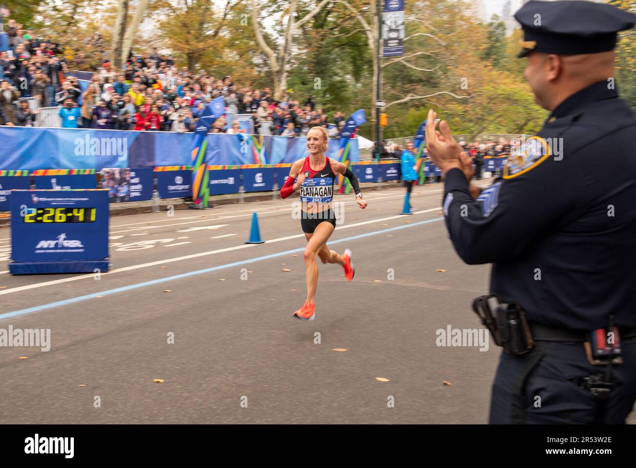 Ein NYPD-Offizier jubelt US-Marathonläufer Shalane Flanagan an an, während sie den New York City Marathon 2017 im Central Park, Manhattan, New York City gewinnt Stockfoto