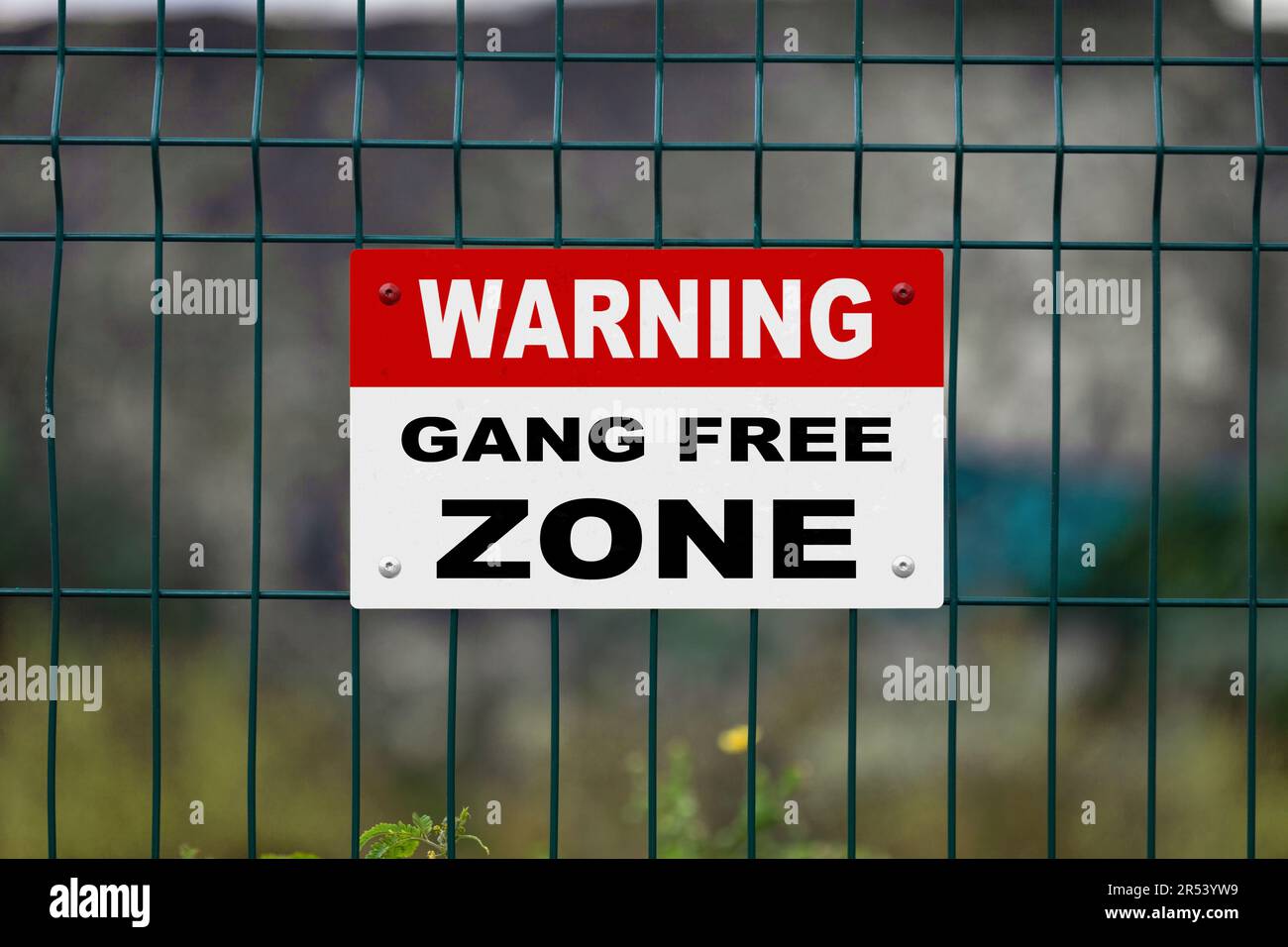 Rot ein weißes Warnschild an einem Zaun mit der Aufschrift „Warnung - Gang free Zone“ und einer Leerstelle darunter. Stockfoto