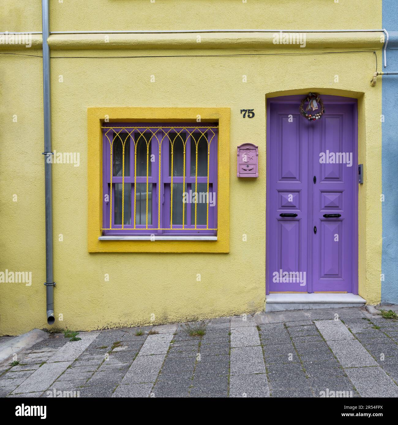 Außenfassade eines Wohngebäudes mit gelb und violett bemalten Wänden, violette Tür und schmiedeeiserne Fenster, in einer engen Straße, Uskudar Viertel, Istanbul, Türkei Stockfoto