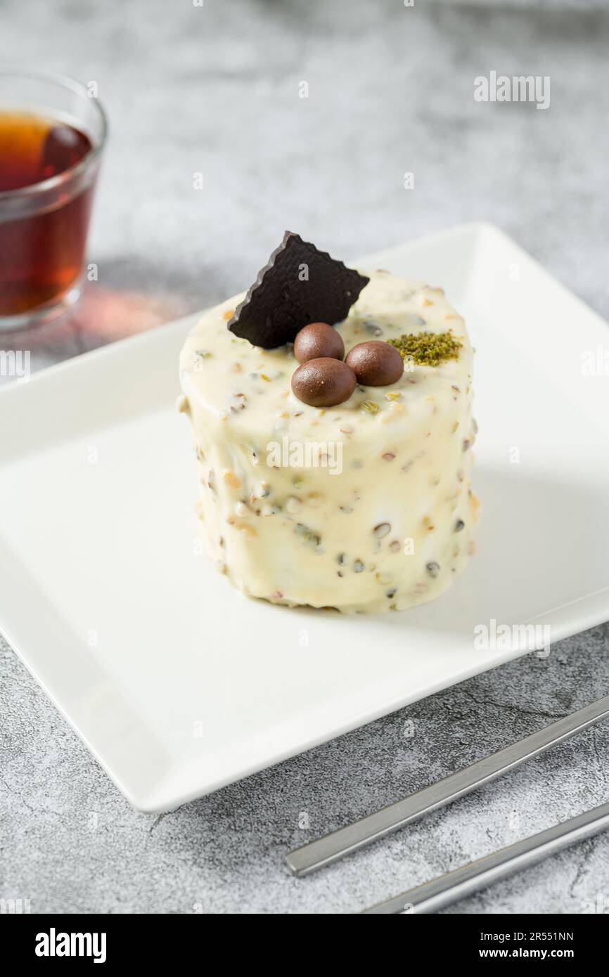 Ein-Personen-Minikuchen mit Pistazien und weißer Schokolade auf einem weißen Porzellanteller Stockfoto