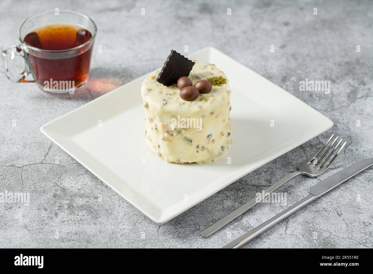 Ein-Personen-Minikuchen mit Pistazien und weißer Schokolade auf einem weißen Porzellanteller Stockfoto