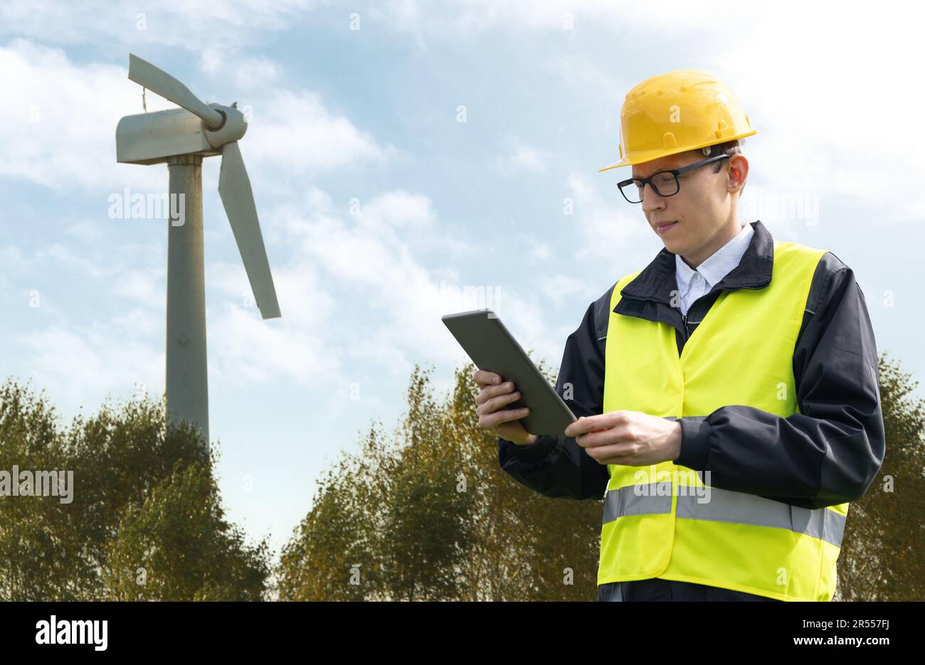 Ingenieur mit Tablet-Computer auf einem Hintergrund einer kaputten Windturbine Stockfoto