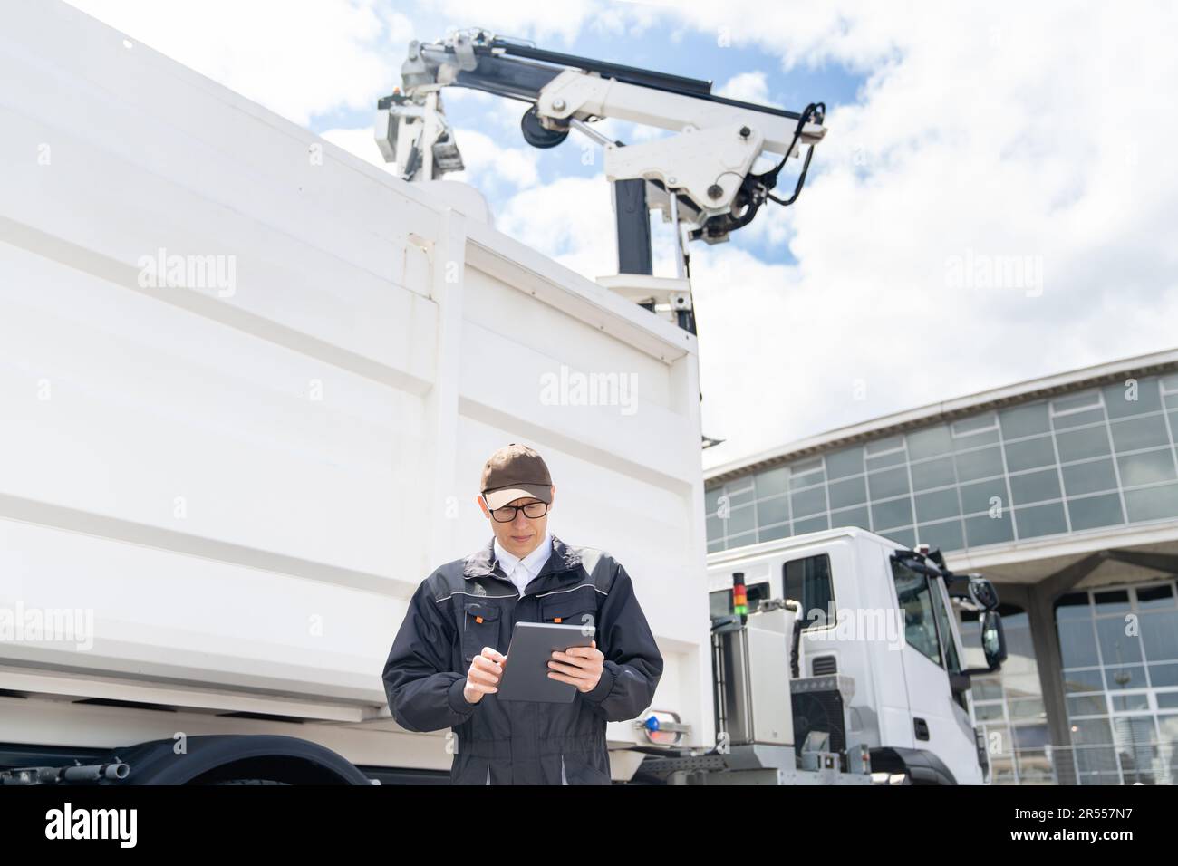 Manager mit einem digitalen Tablet neben dem Müllwagen. Hochwertiges Foto Stockfoto