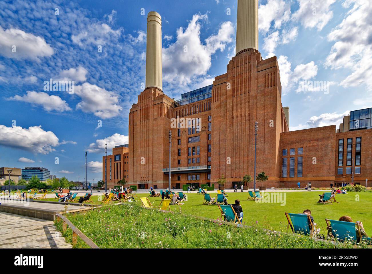 London Wandsworth Battersea Power Station sonnenblauer Himmel wilder Blumengarten und Menschen in Liegestühlen auf einem grünen Rasen Stockfoto