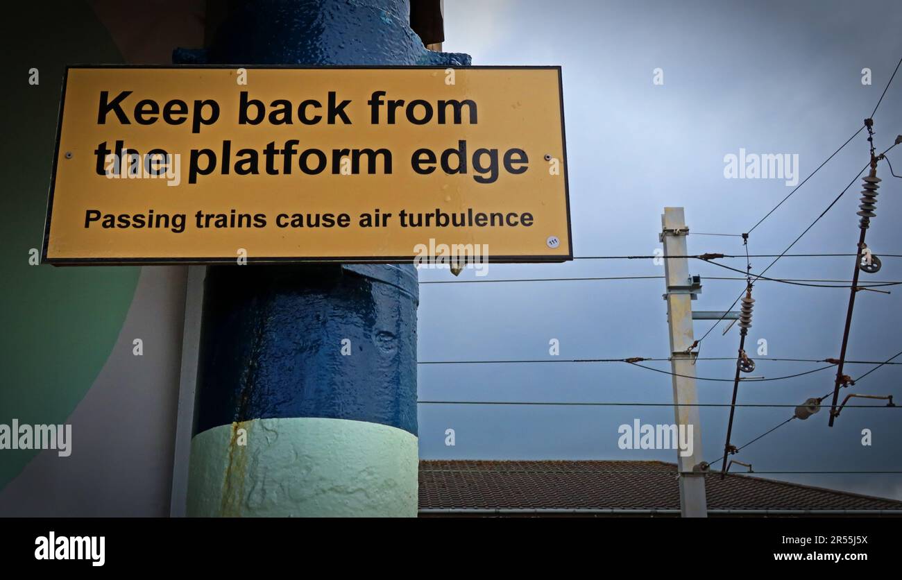 Eisenbahnsicherheitsschild, das die Passagiere warnt, sich vom Bahnsteig zurückzuhalten, da Luftturbulenzen von vorbeifahrenden Zügen auftreten, fotografiert an einem britischen Bahnhof Stockfoto