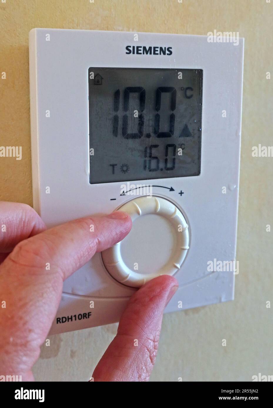 Einstellen eines Thermostats bei kalter Witterung (10deg) zum Einschalten der Heizung mit einem wandmontierten Siemens RDH10RF-Regler Stockfoto