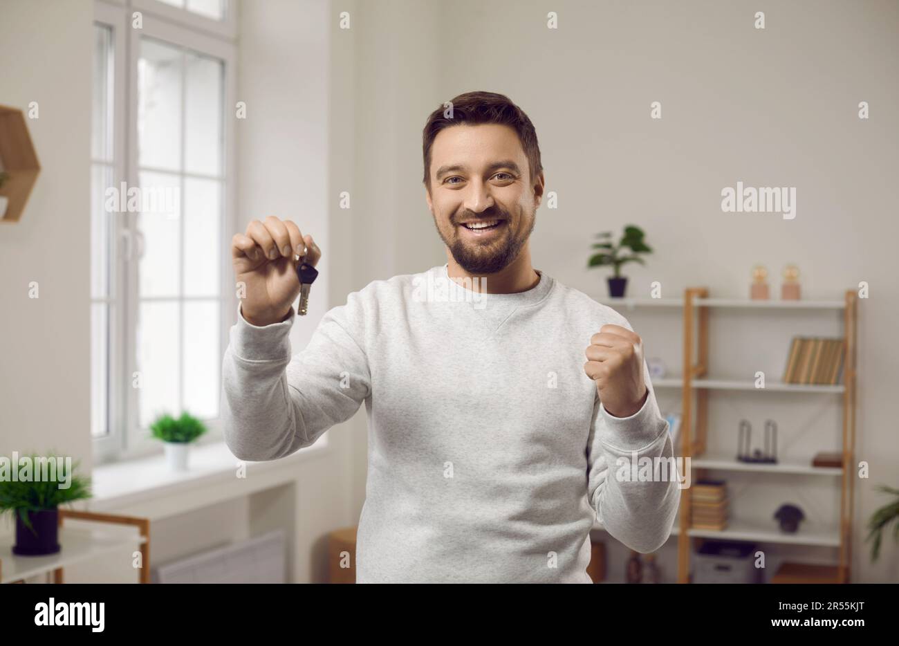 Porträt eines jungen, fröhlich lächelnden, attraktiven Mannes mit Schlüsseln in der Hand. Stockfoto