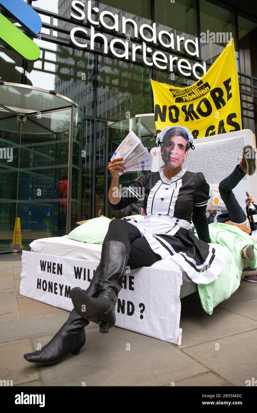 London, England, Großbritannien 01/06/2023 Money Rebellion Aktivisten veranstalten bei Standard Chartered eine satirische „Menage a trois“ zwischen dem CEO Bill Winters und seinen fossilen Brennstofffreunden, Öl und Kohle, während Rishi Sunak Champagner serviert und gelegentlich mit einem Haufen Geld angeboten wird. Stockfoto