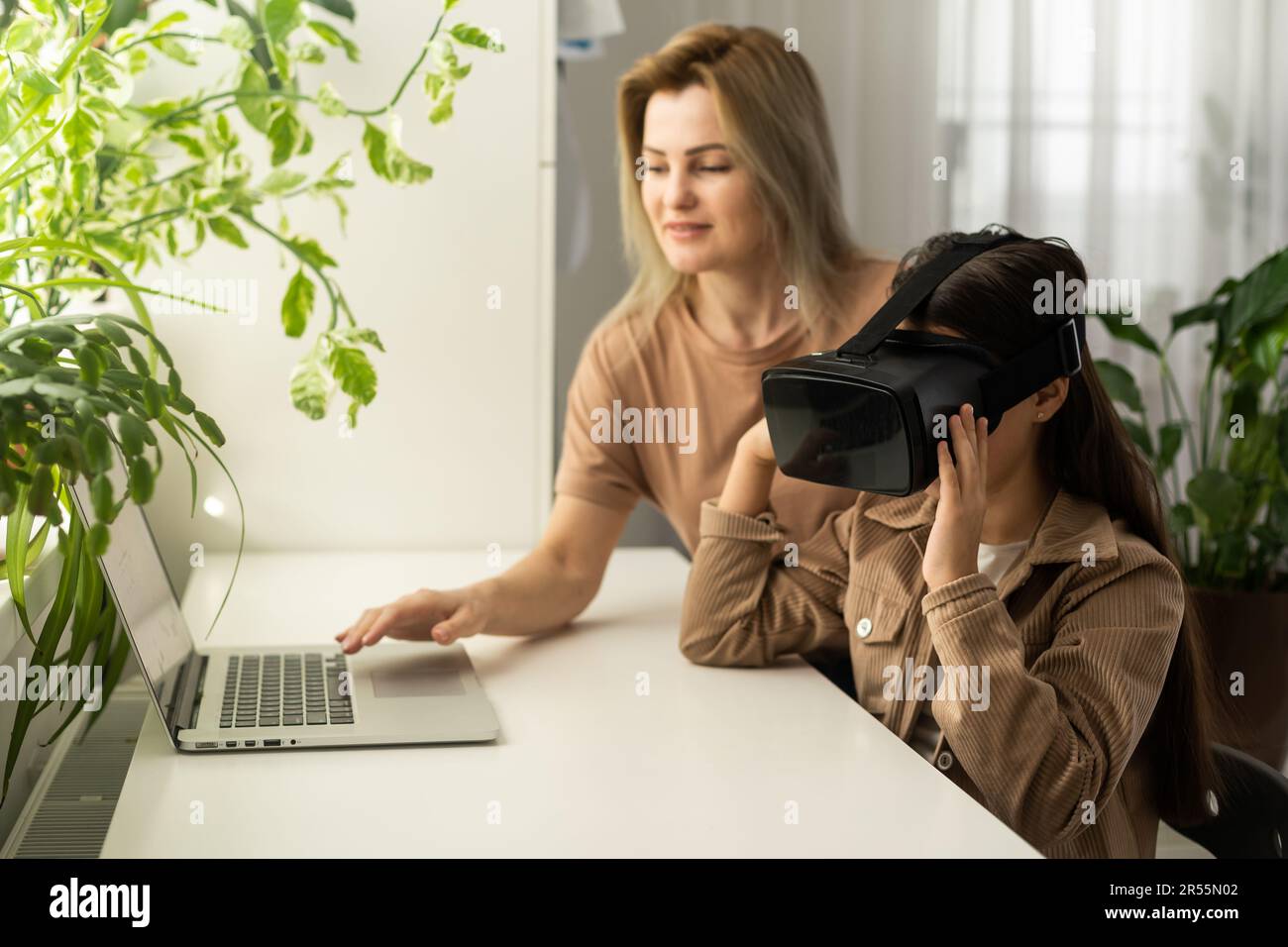 Familien und neue Technologien. Lächelnde Arbeit-zu-Hause-Mutter, die mit ihrer Tochter einen VR-Helm trägt und die virtuelle Realität erforscht. Neugieriges Teenager-Mädchen Stockfoto