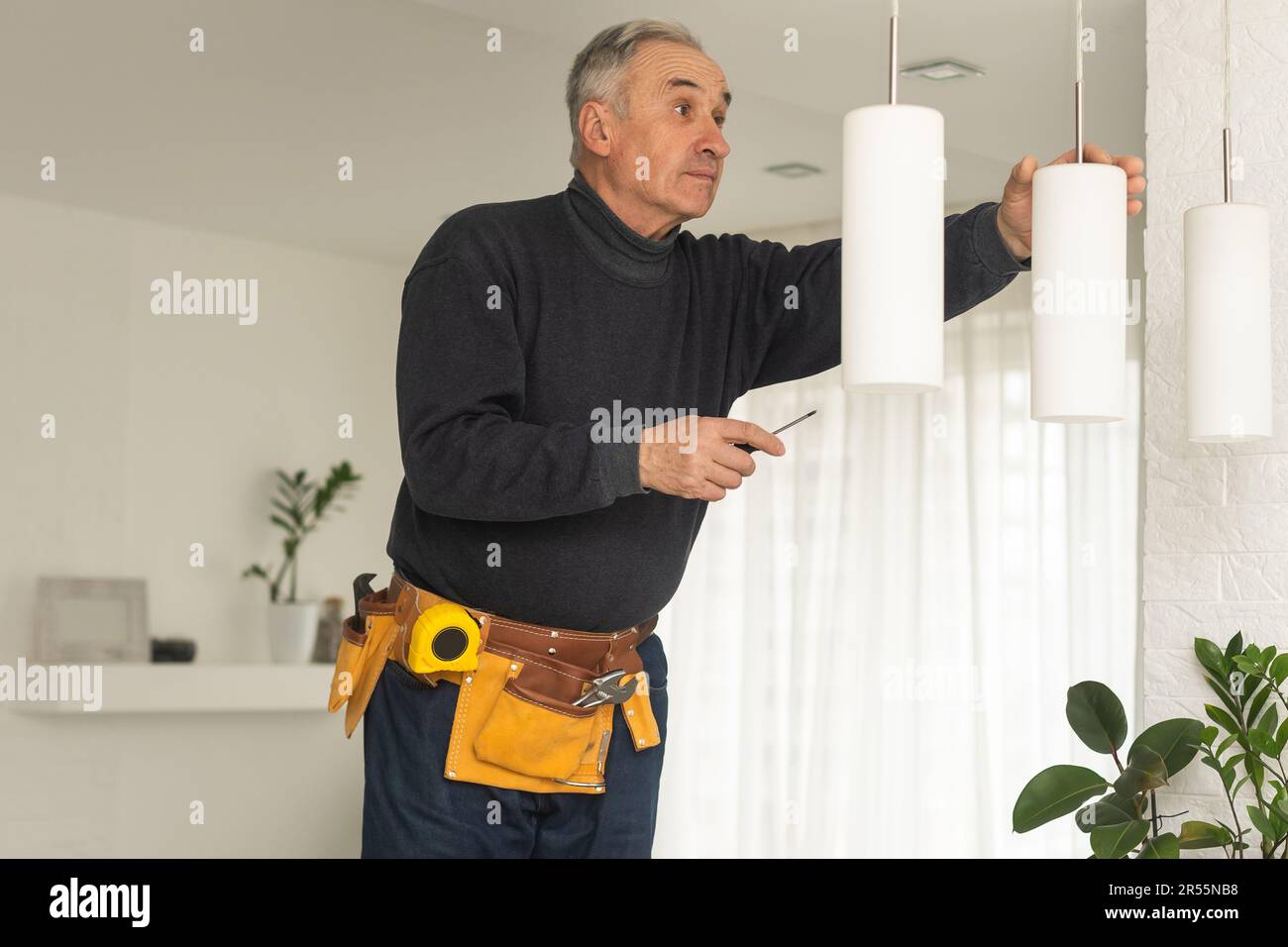 Älterer Mann, der die Glühbirnen wechselt : Rentner, der Hausarbeiten erledigt, Glühbirnen und Kuppeln ersetzt, geschickt dekoriert. Stockfoto
