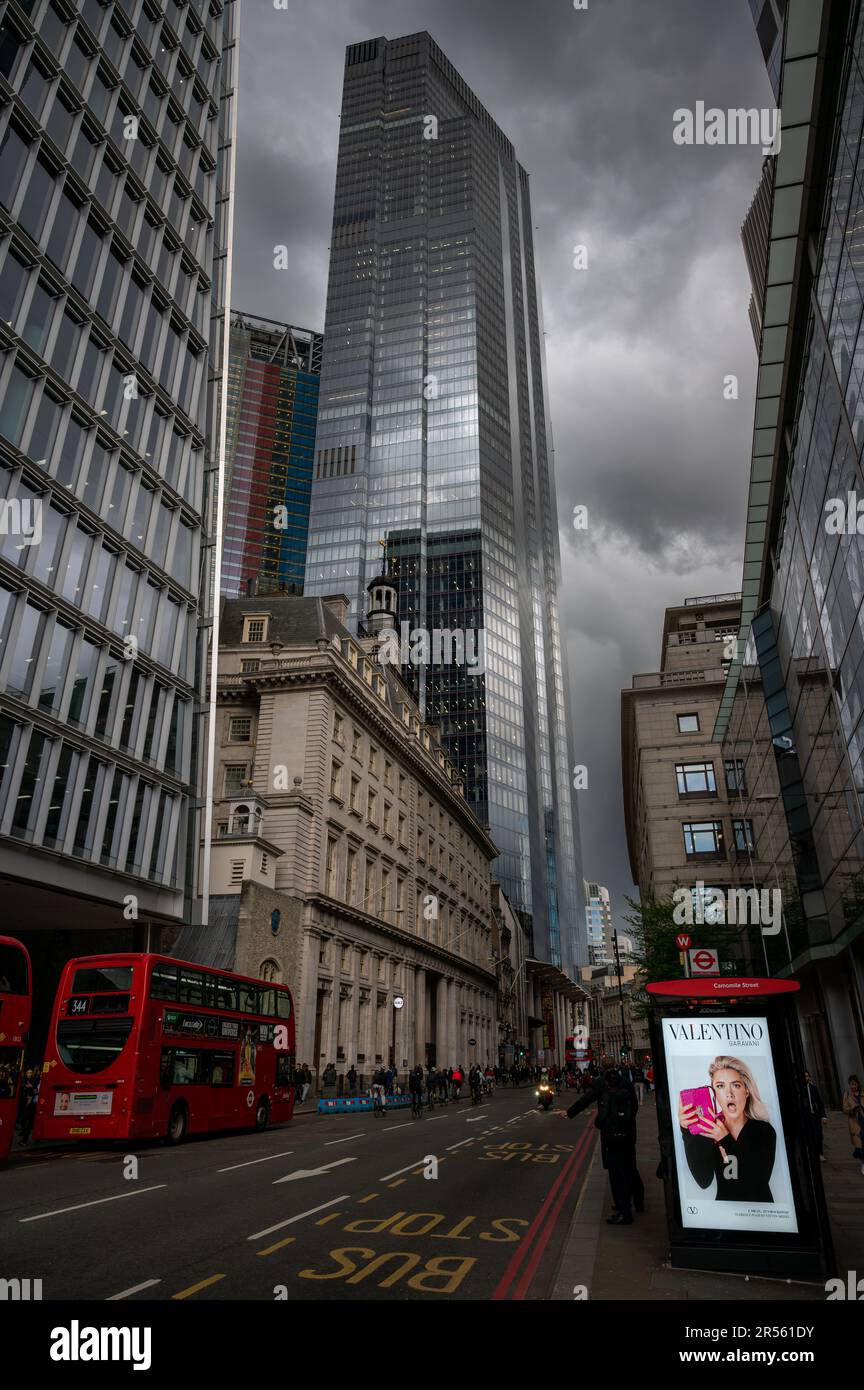 London, Vereinigtes Königreich: Bishopsgate in der Londoner City mit Personen und roten Bussen. Der 22 erbaute Wolkenkratzer Bishopsgate befindet sich vor dem Hintergrund dunkler Sturmwolken. Stockfoto