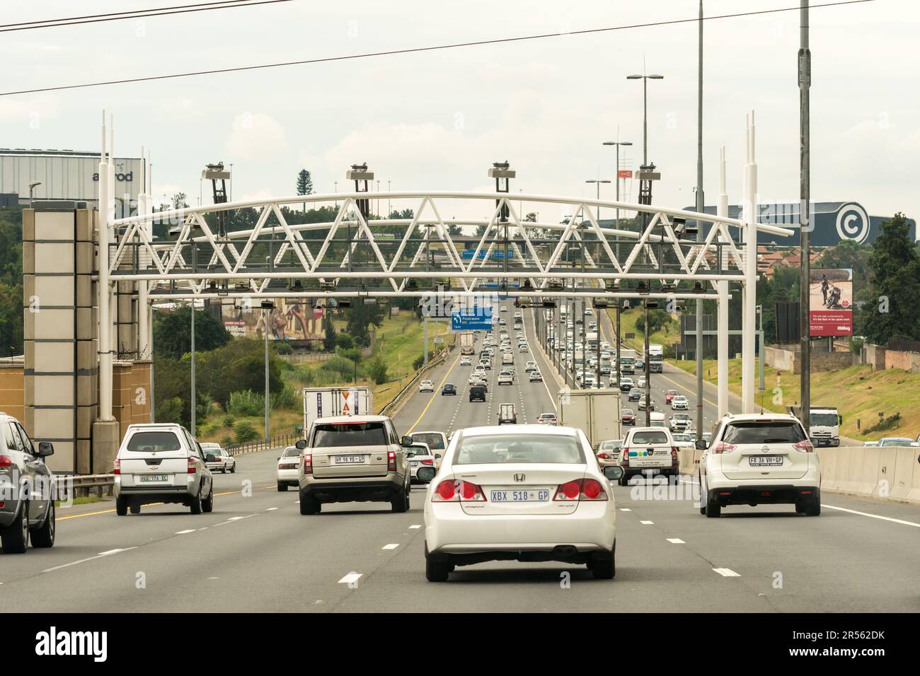 Autos, Fahrzeuge, Autofahrer fahren auf einer Nationalstraße oder Autobahn unter Mautstellen, die Mautgebühren oder elektronische Mautgebühren in Gauteng, Südafrika, erheben Stockfoto