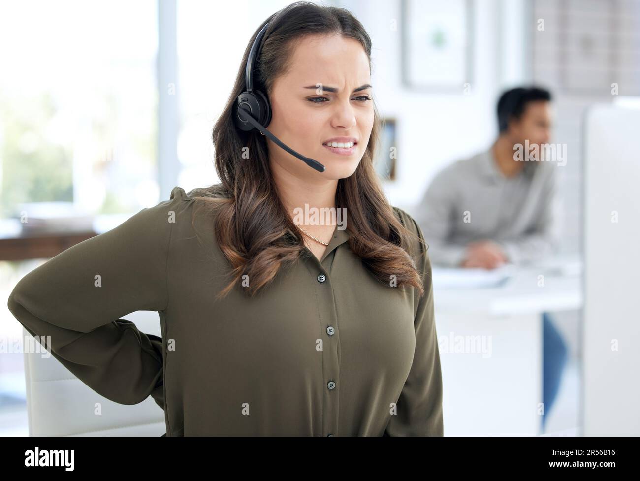 Callcenter, Rückenschmerzen und Frau, Agent oder Berater am Computer für Burnout, Gesundheitsproblem und Stress. Telekommunikation, Kundendienst und Leiharbeiter Stockfoto