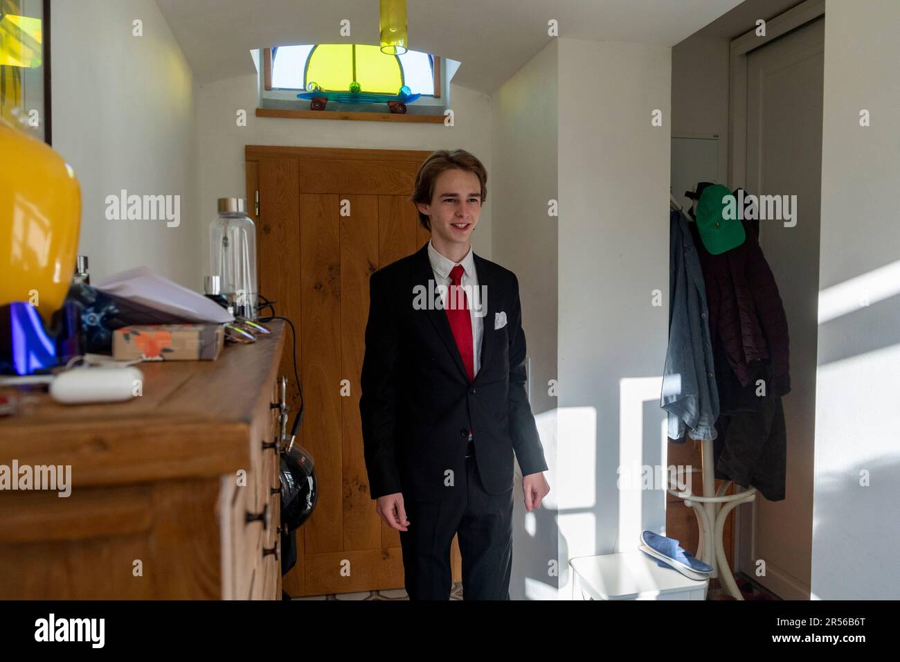 Ein Teenager in schwarzem Anzug geht gleich von zu Hause, um eine Sekundarschulabschlußprüfung zu bestehen Stockfoto